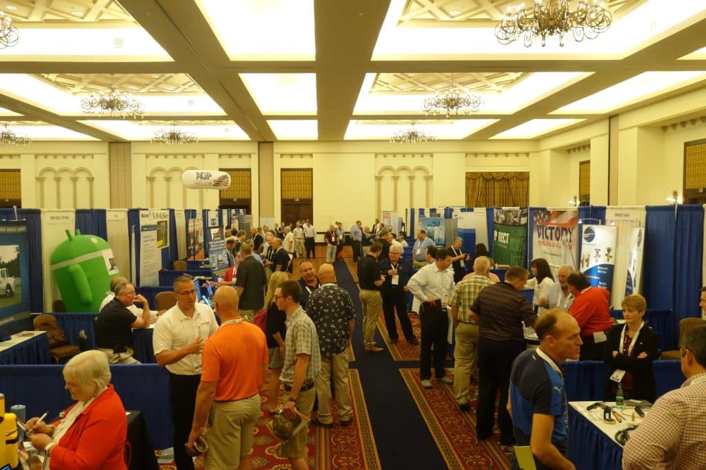 Busy convention hall with booths and attendees networking at an expo event.