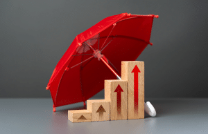 Red umbrella shielding a rising set of wooden blocks with upward arrows, symbolizing growth and protection in business progress.