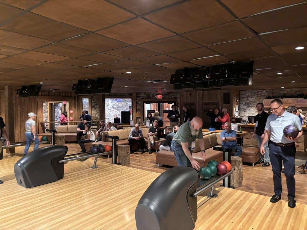 Busy bowling alley with players and spectators around seating areas and bowling lanes in the foreground