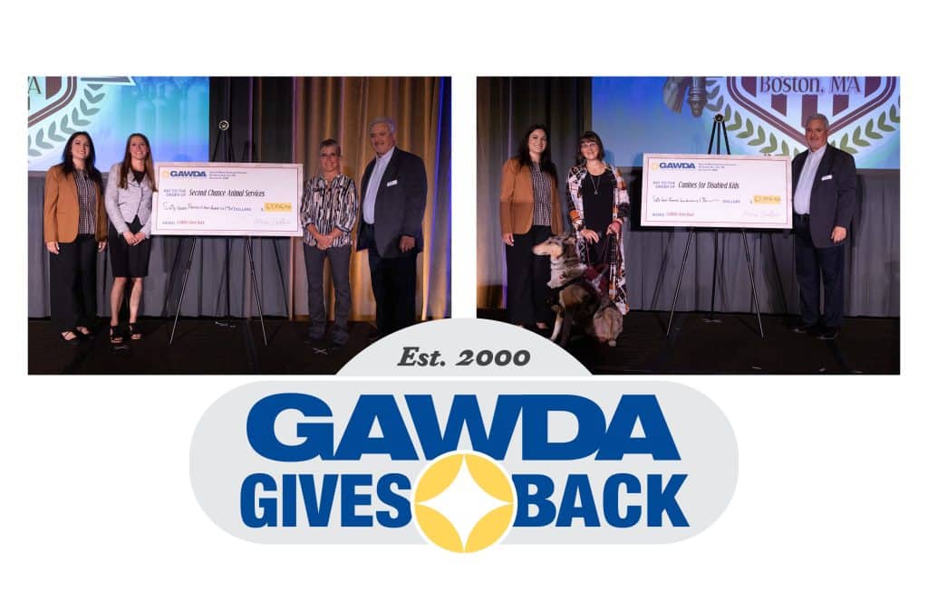 Group of recipients on a stage posing with oversized ceremonial checks during a GAWDA Gives Back event, backdrop shows the GAWDA logo.