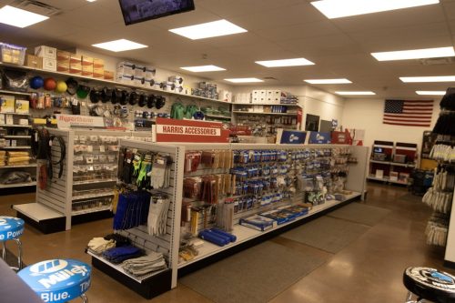 A hardware store aisle with gloves, tools, and accessories; a red Harris Accessories sign in the foreground.