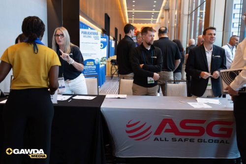 Registration desk at a conference expo with an ASC All Safe Global banner and attendees talking nearby.