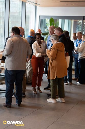 Group of professionals networking in a modern office lobby near large windows with natural light.