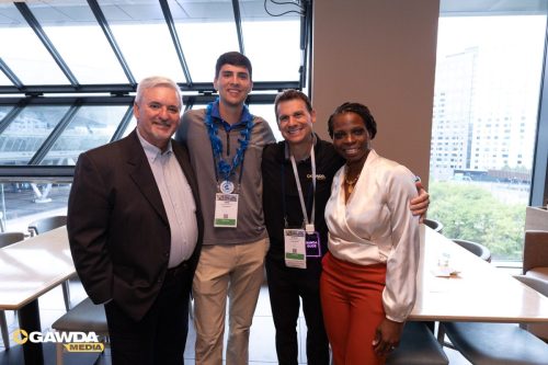 Four professionals posing together for a photo at a conference, smiling, with name badges and a GAWDA Media logo visible in the corner.