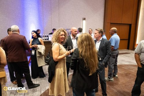 Group of professionals chatting and holding wine glasses at a hotel bar during a networking event.