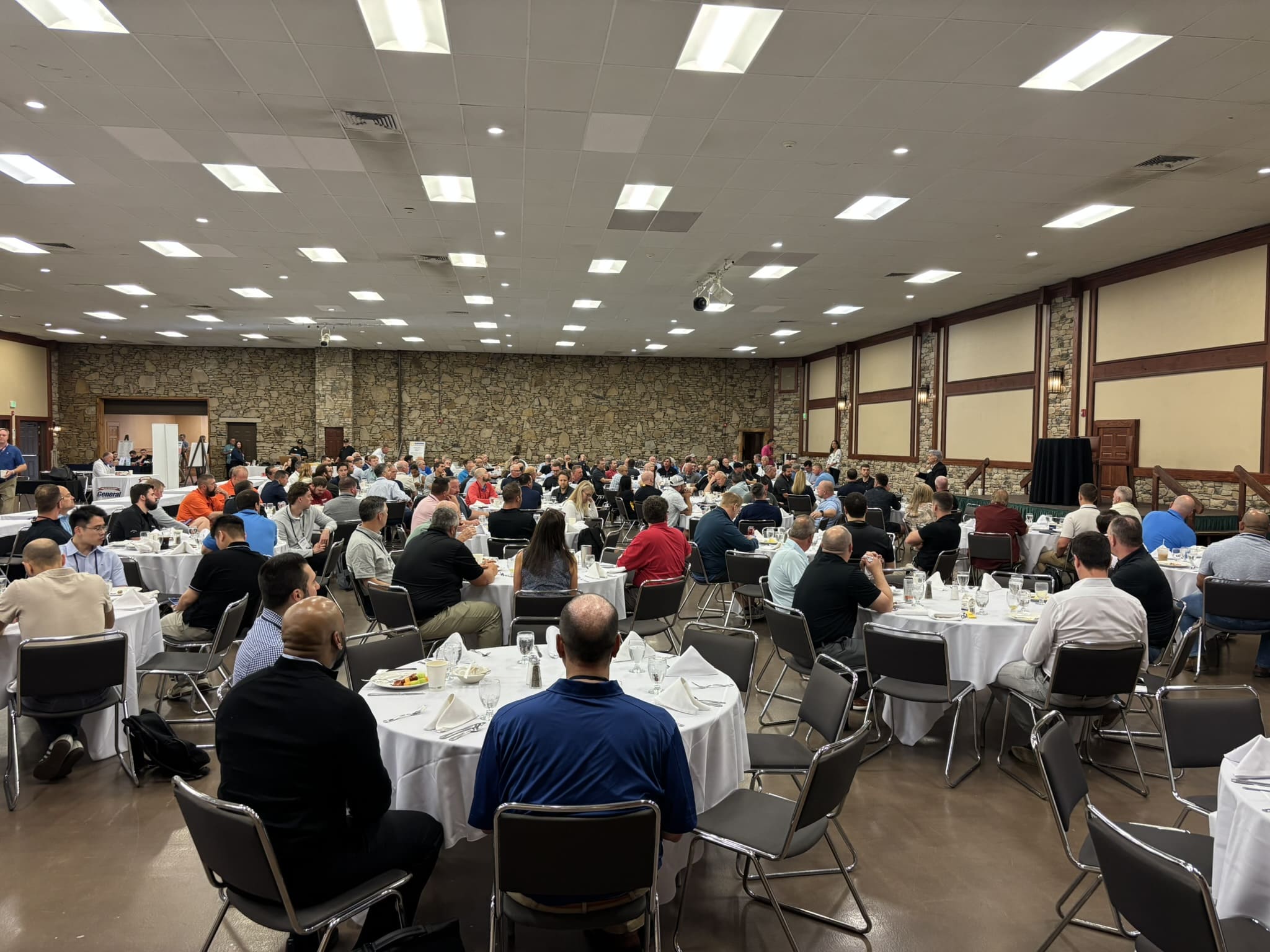 Large banquet hall filled with people seated at round tables for a formal meal.