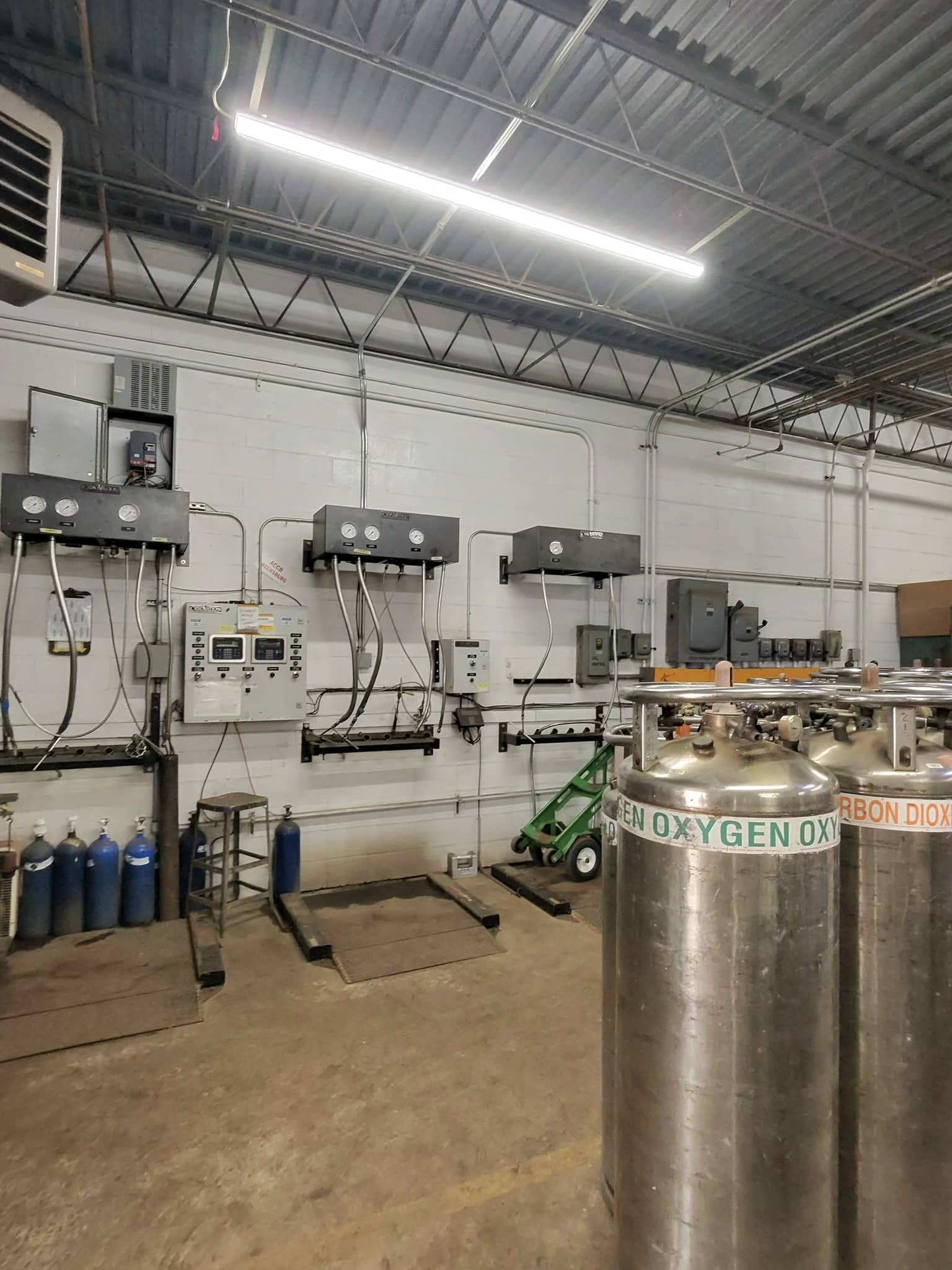 Industrial room with large oxygen tanks labeled Oxygen, along with pipes and wall-mounted controls in the background.