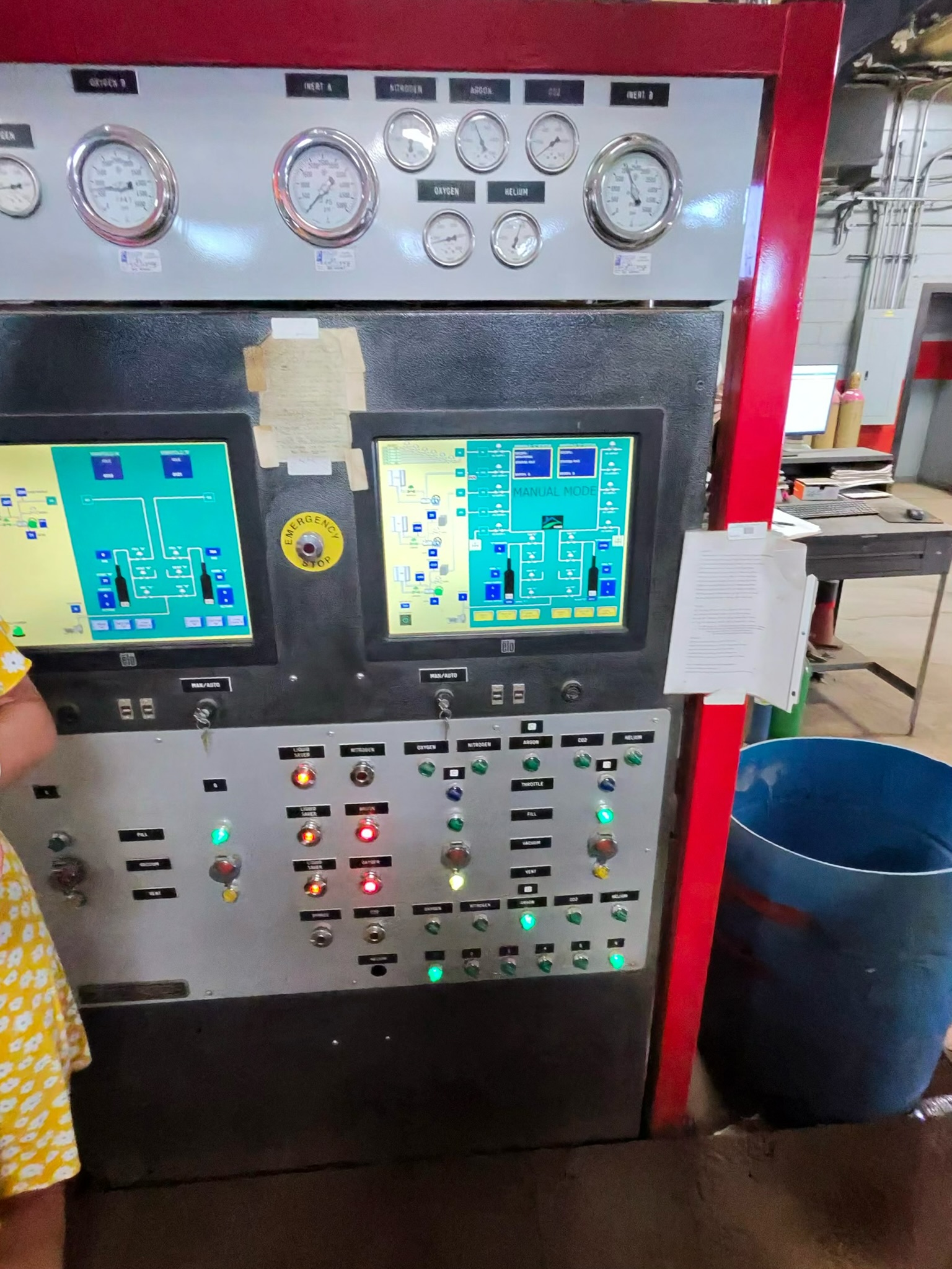 Industrial control panel with multiple gauges and two digital screens, showing status indicators and controls in a red-framed cabinet.
