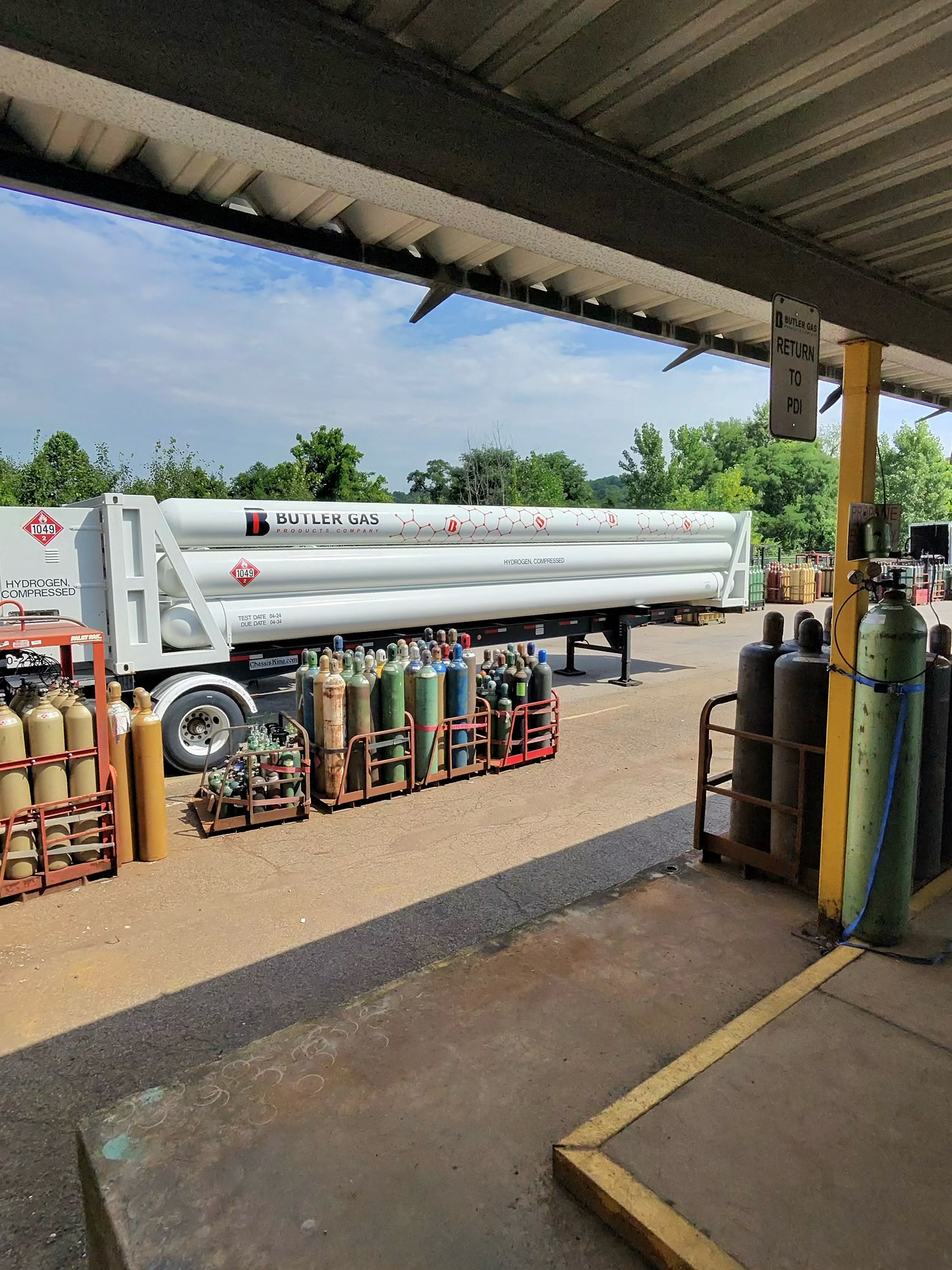 Gas cylinder storage area with stacked propane tanks under a canopy; labels read Butler Gas and hydrogen as contents of cylinders.